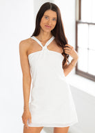 Woman wearing a white dress with a halter neck design against a light background