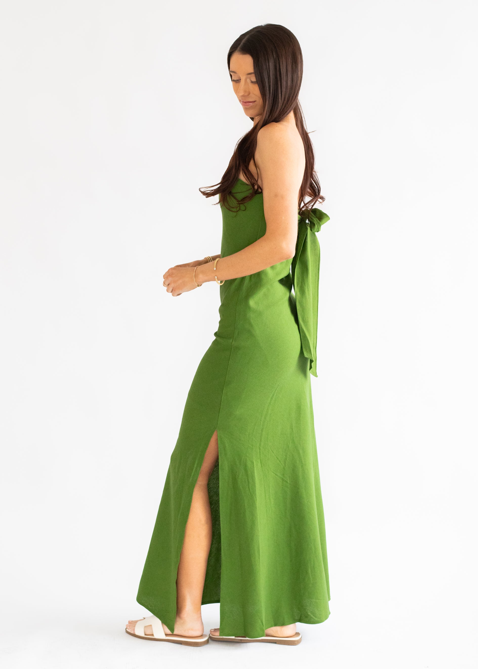 Woman wearing a green dress with a slit on a white background