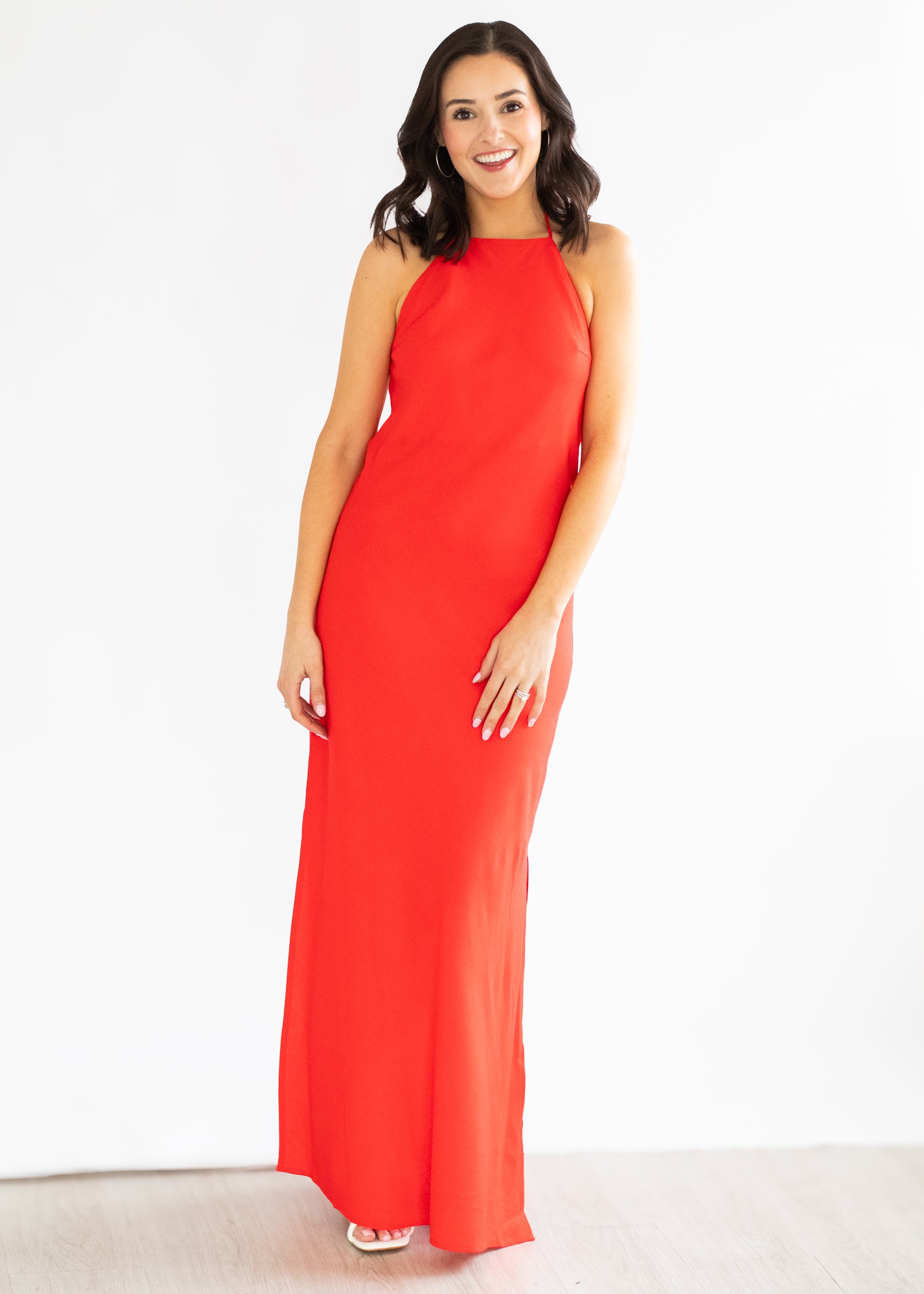 Woman wearing a red halter neck dress on a white background