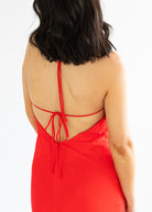 Red open-back dress worn by a person on a white background