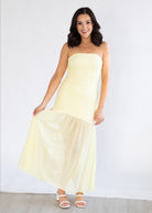 Woman wearing a strapless yellow dress against a white background