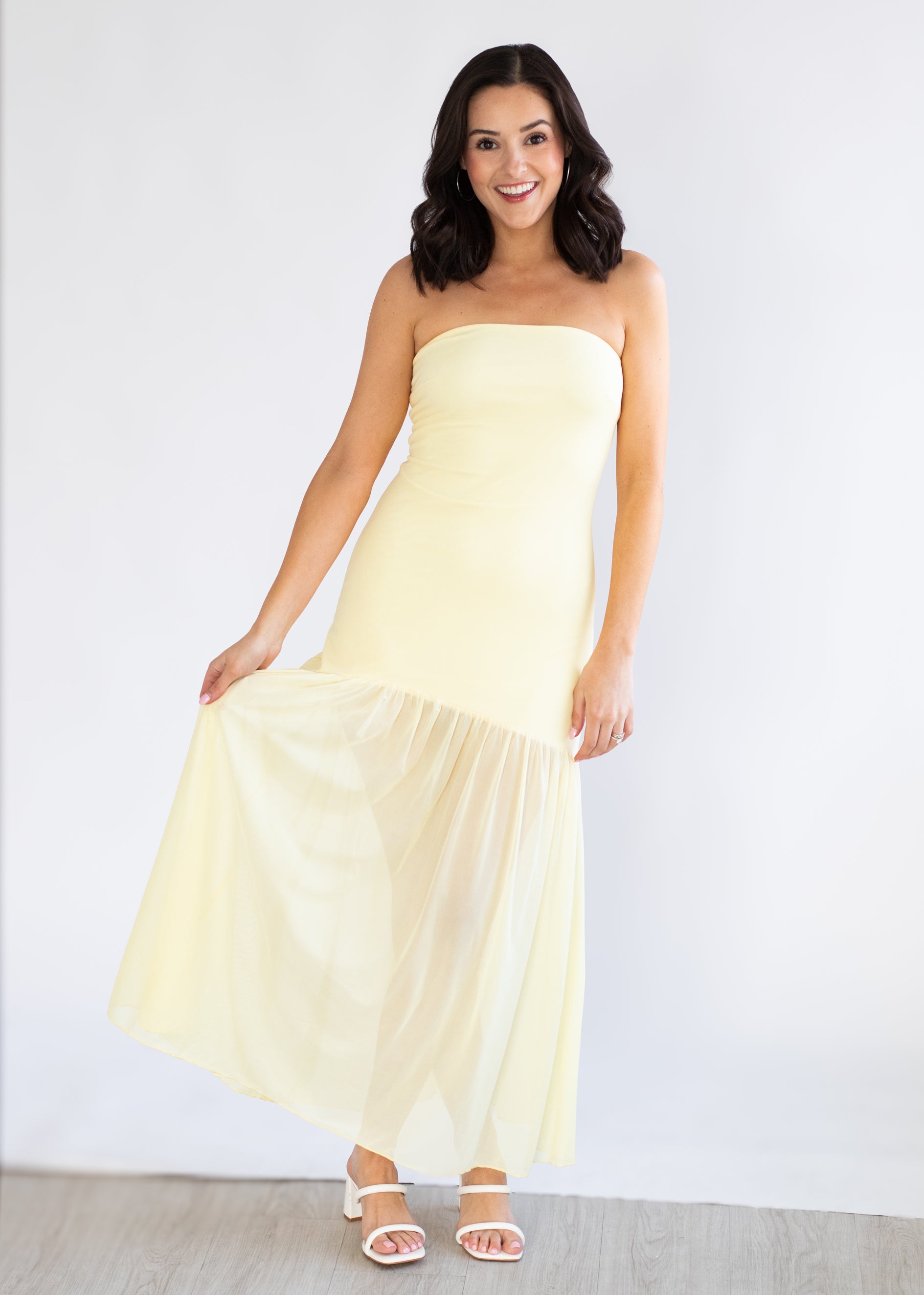 Woman wearing a strapless yellow dress against a white background