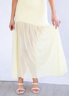 Person wearing a light yellow dress with a plain background