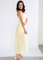Woman wearing a light yellow strapless dress against a white background