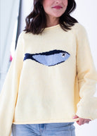 Person wearing a yellow sweater with a blue whale design.