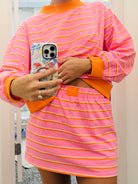 Person wearing a pink and orange striped outfit holding a phone.