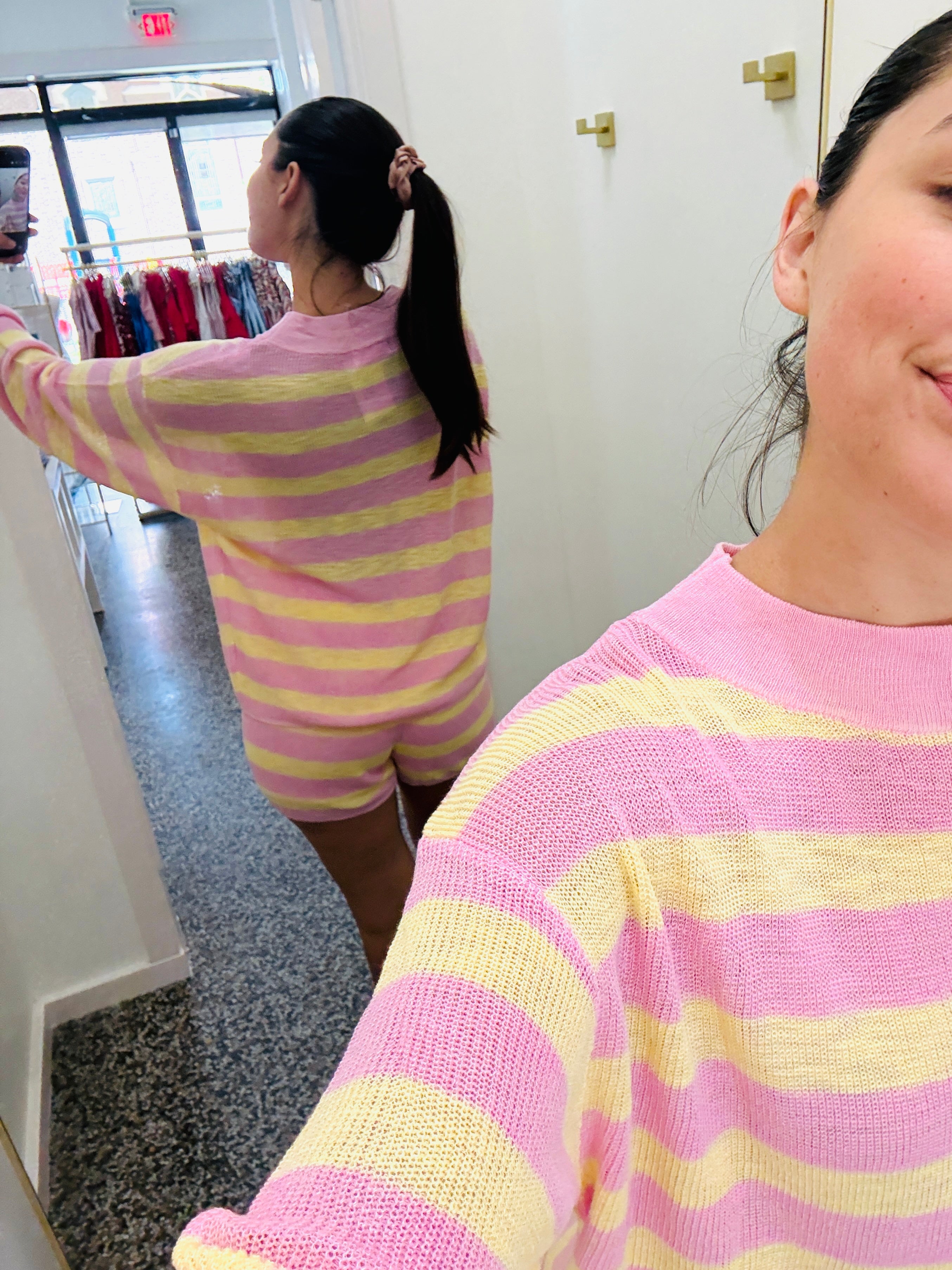 Two people wearing pink and yellow striped outfits in a store setting.