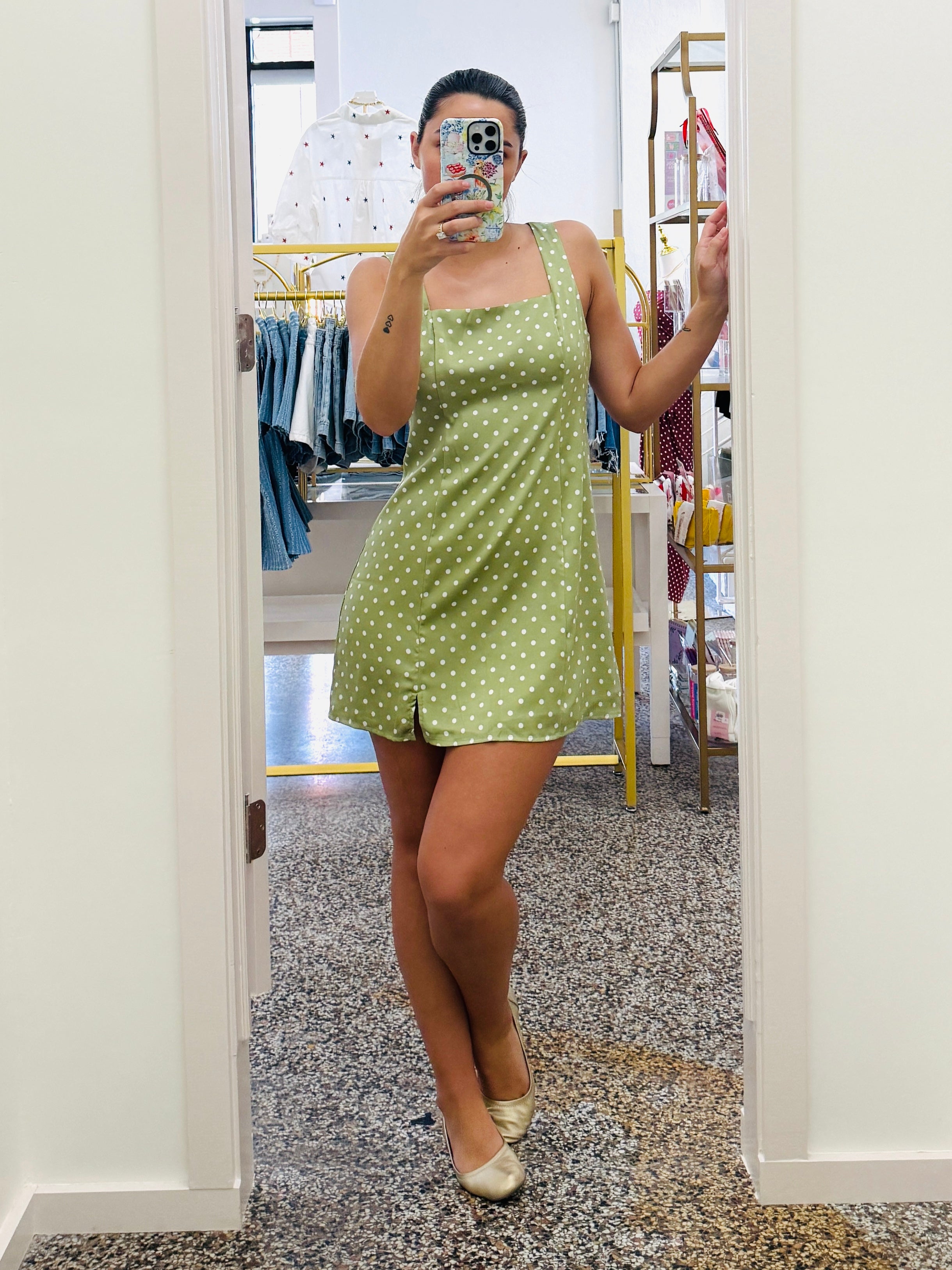 Person wearing a green polka dot dress taking a mirror selfie.