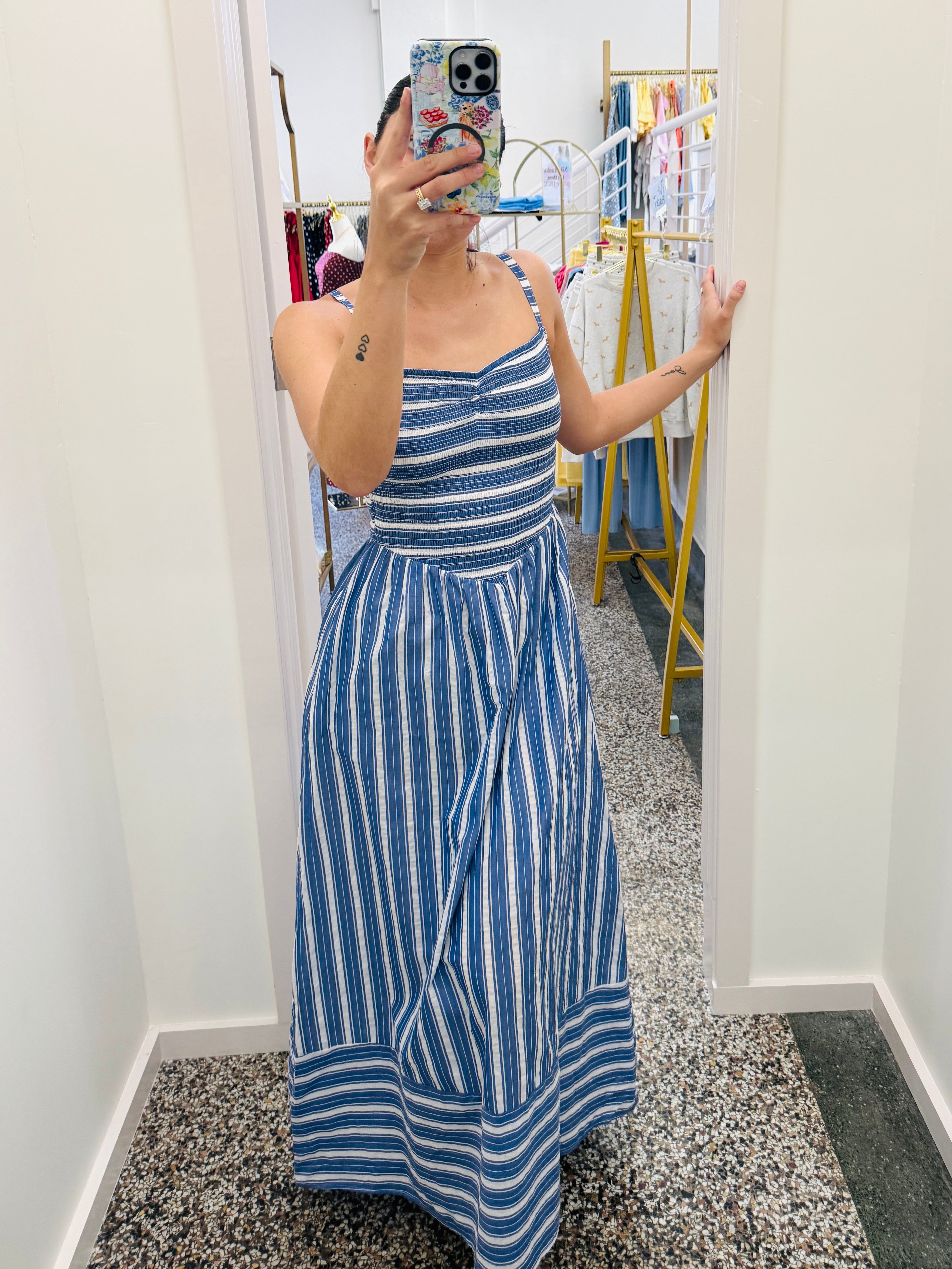 Person wearing a blue and white striped dress in a fitting room.