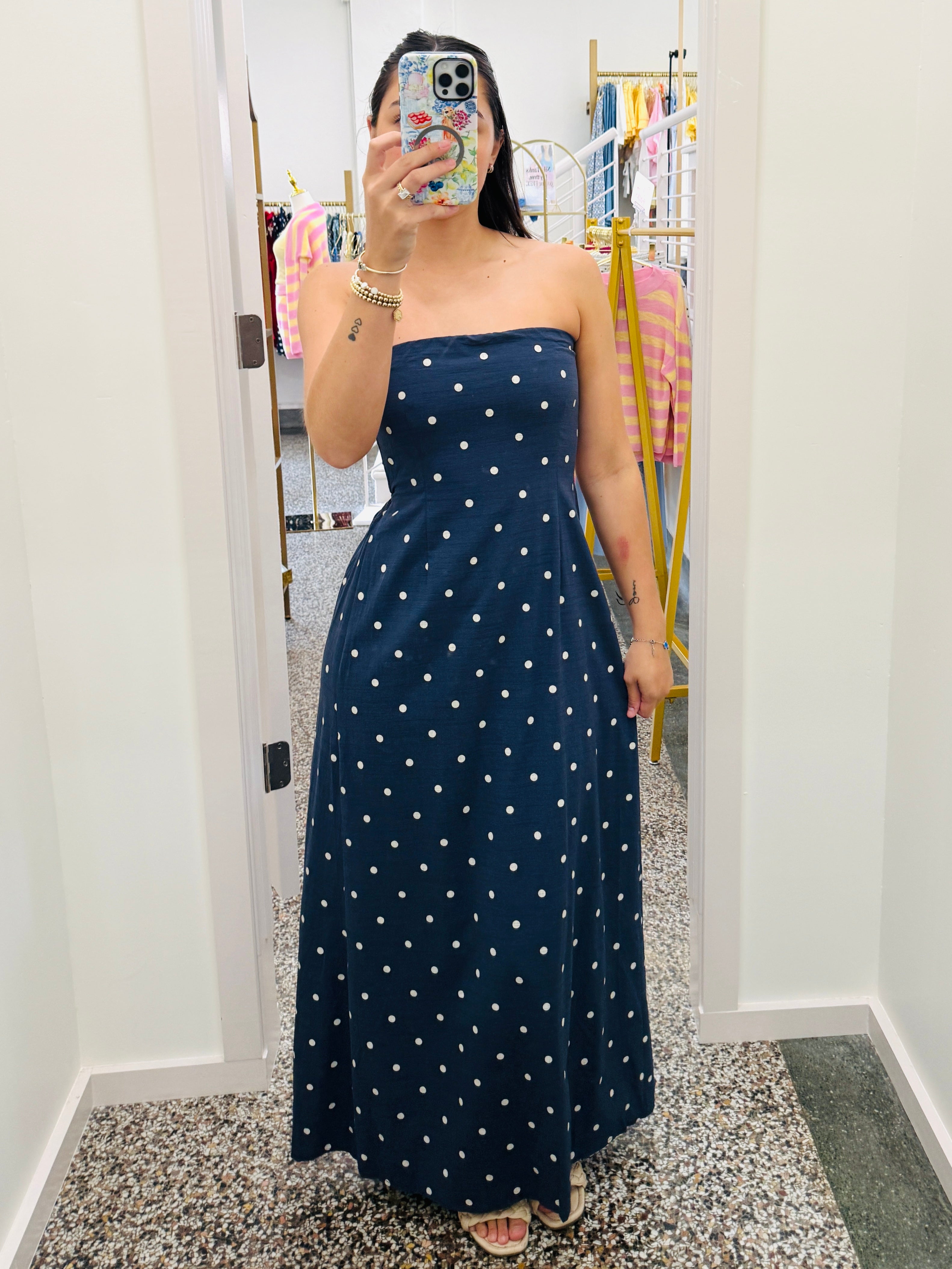 Woman wearing a navy blue strapless dress with white polka dots in a room.