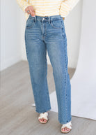 Person wearing blue jeans and a yellow striped shirt on a light wooden floor.