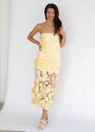 Woman wearing a yellow floral dress against a white background