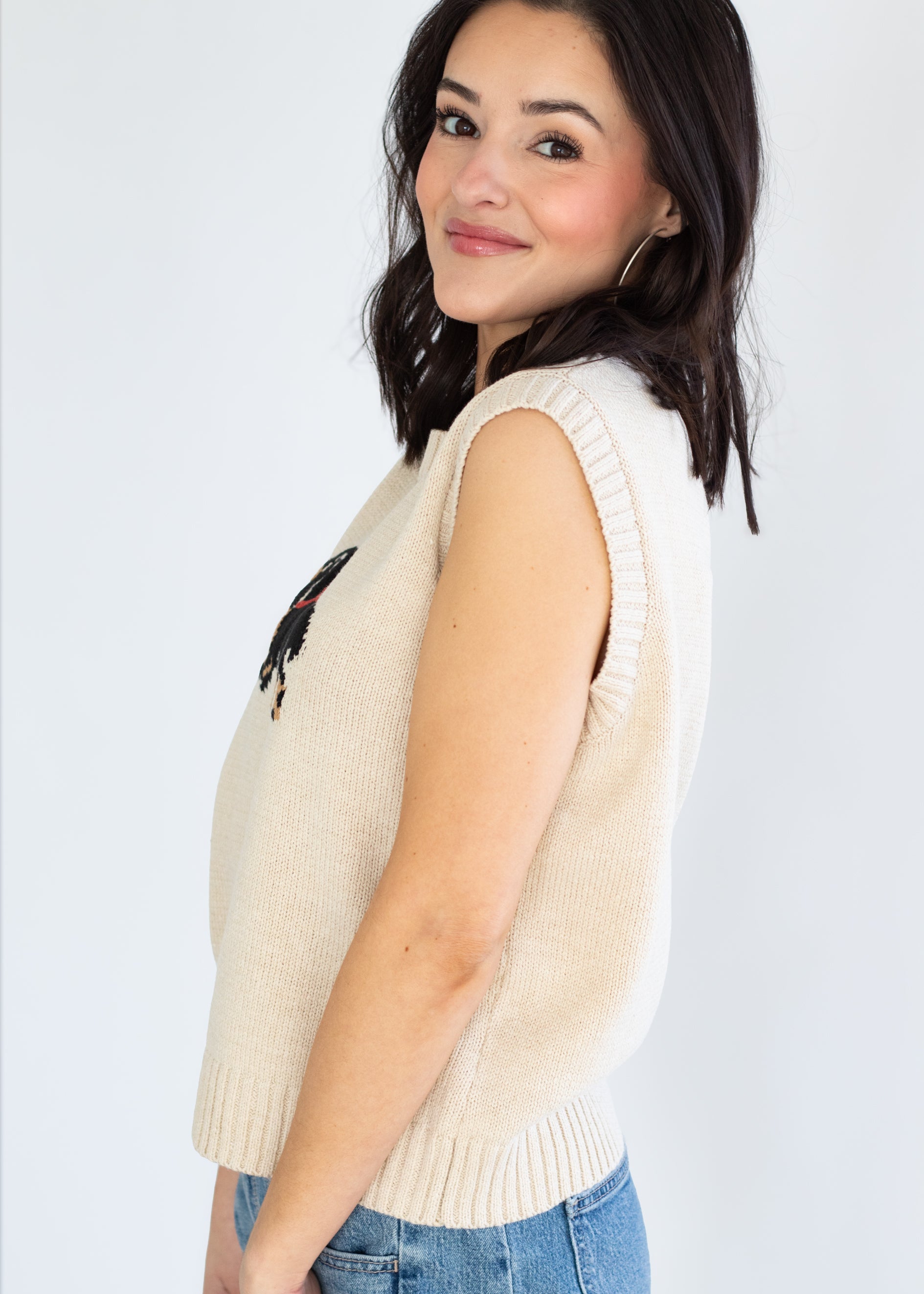 Woman wearing a beige sleeveless sweater vest on a white background