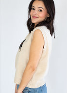 Woman wearing a beige sleeveless sweater vest on a white background