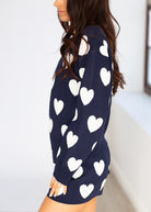 Navy blue dress with white heart patterns worn by a person against a white background