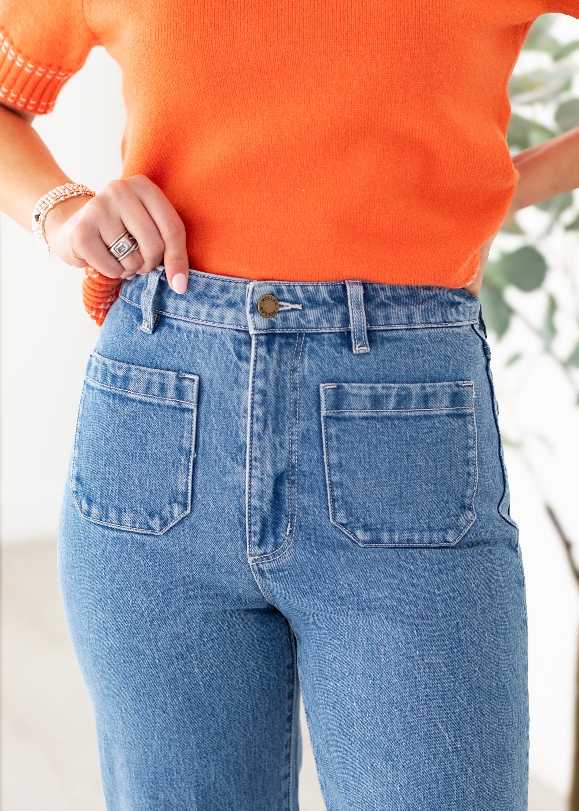Person wearing blue jeans and an orange sweater with a blurred background