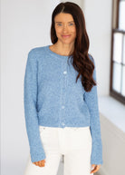 Woman wearing a blue knitted cardigan in a bright room