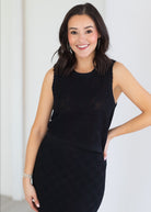 Woman wearing a black sleeveless dress against a white background