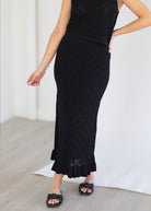 Person wearing a black dress with a textured pattern on a light background