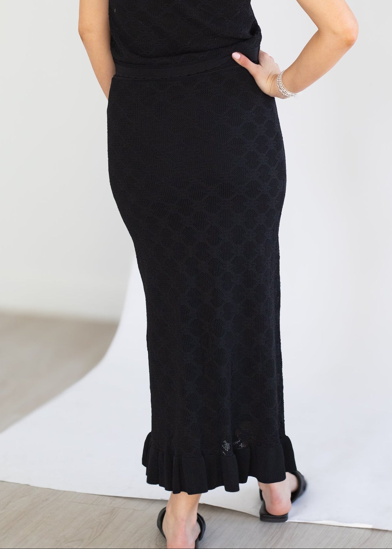 Woman wearing a black sleeveless dress with a textured pattern on a white background