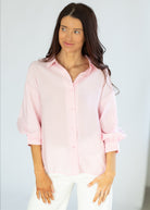Woman wearing a light pink shirt against a plain background