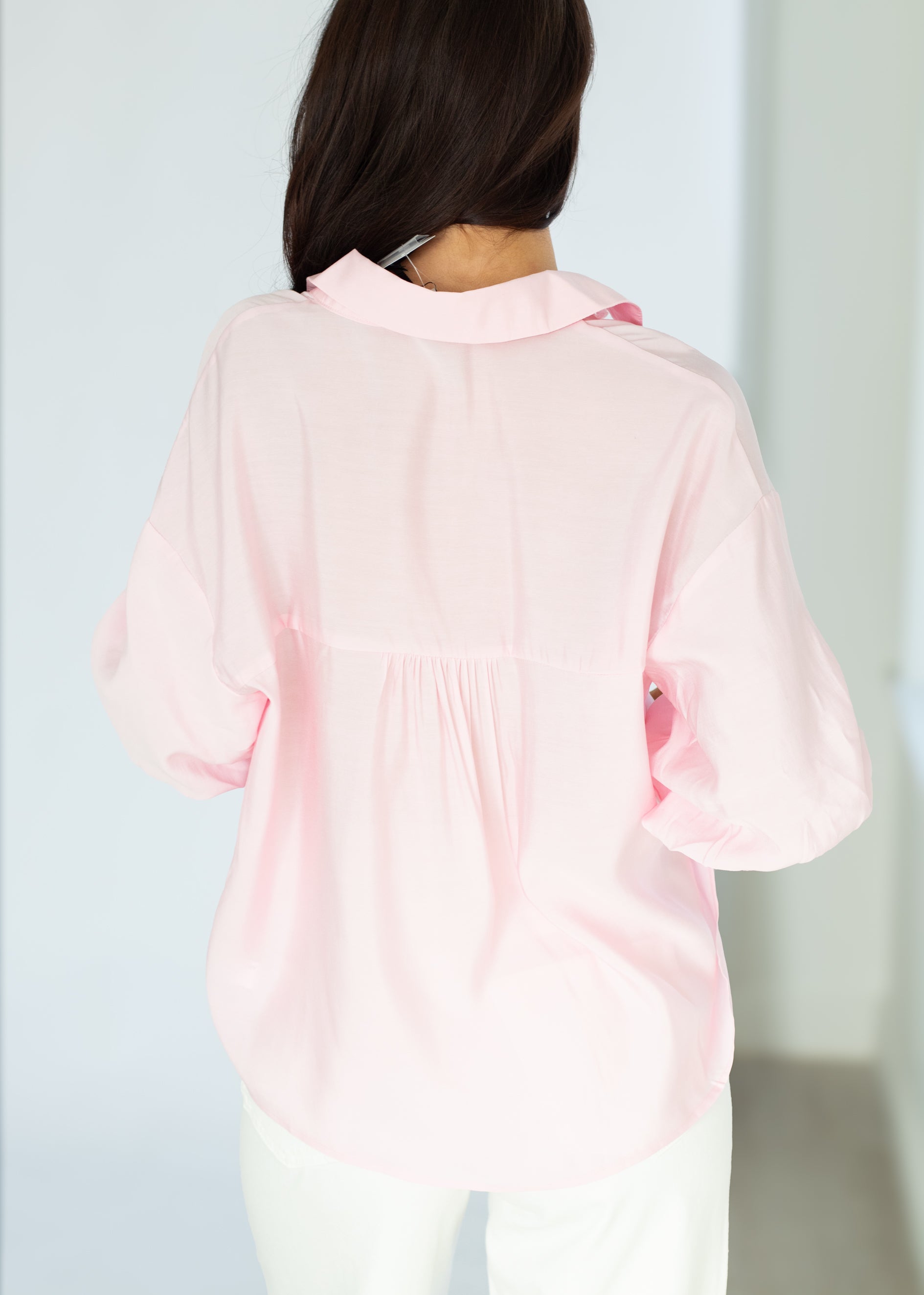 Person wearing a light pink blouse with a blurred background