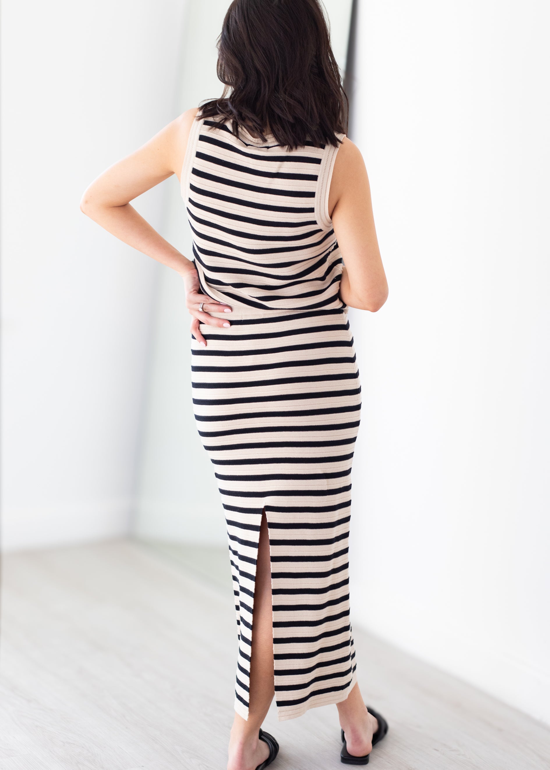 Woman wearing a black and white striped dress with a slit on a plain background