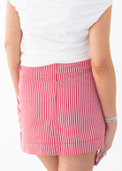 Red and white striped skirt worn by a person on a white background