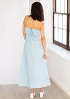 Woman wearing a light blue strapless dress in a minimal indoor setting