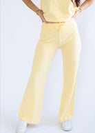 Person wearing a yellow outfit with wide-leg pants on a white background