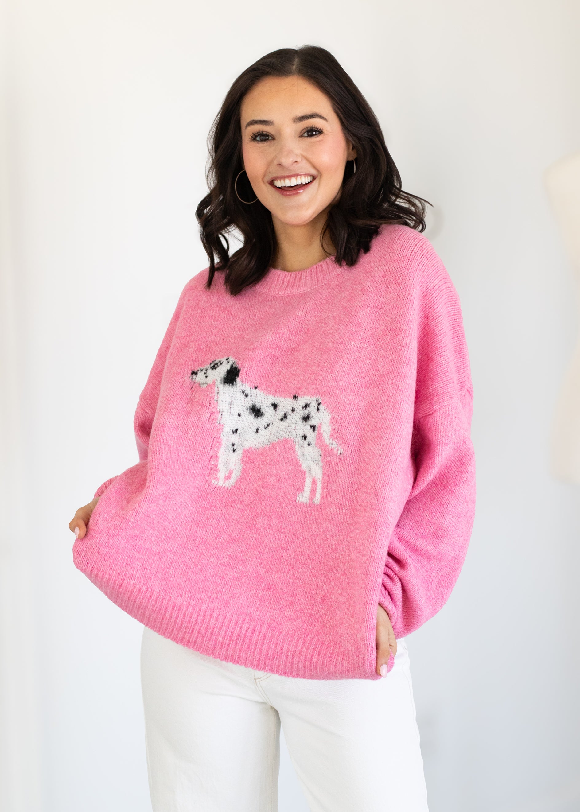 Woman wearing a pink sweater with a dog design on a white background
