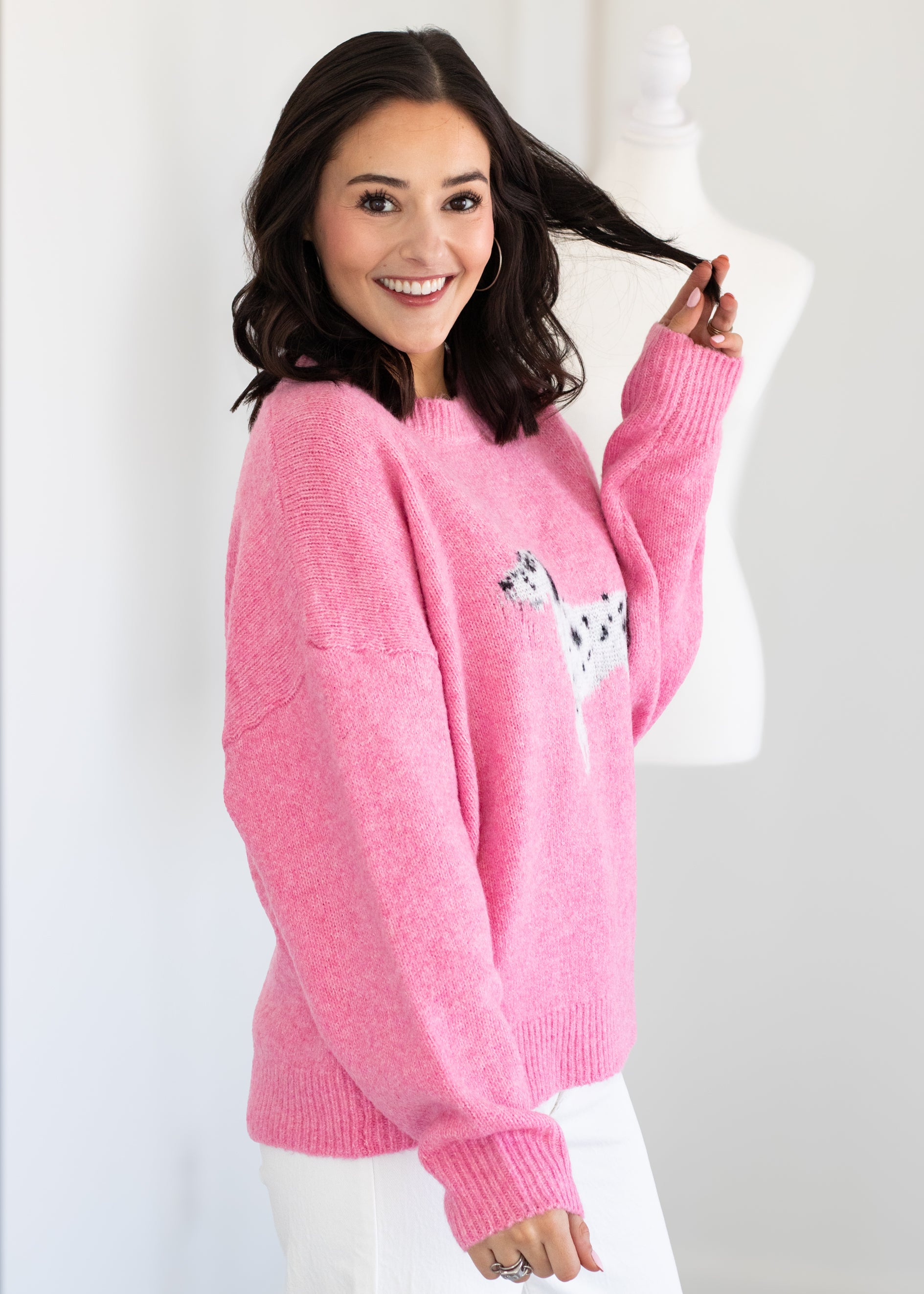 Person wearing a pink sweater with a small design on a white background