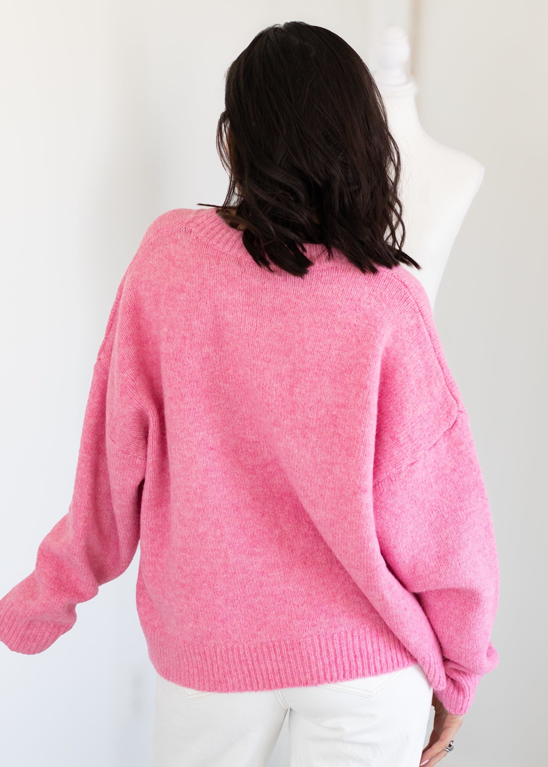 Person wearing a pink sweater against a white background