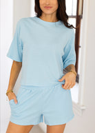 Woman wearing a light blue striped outfit with shorts indoors.