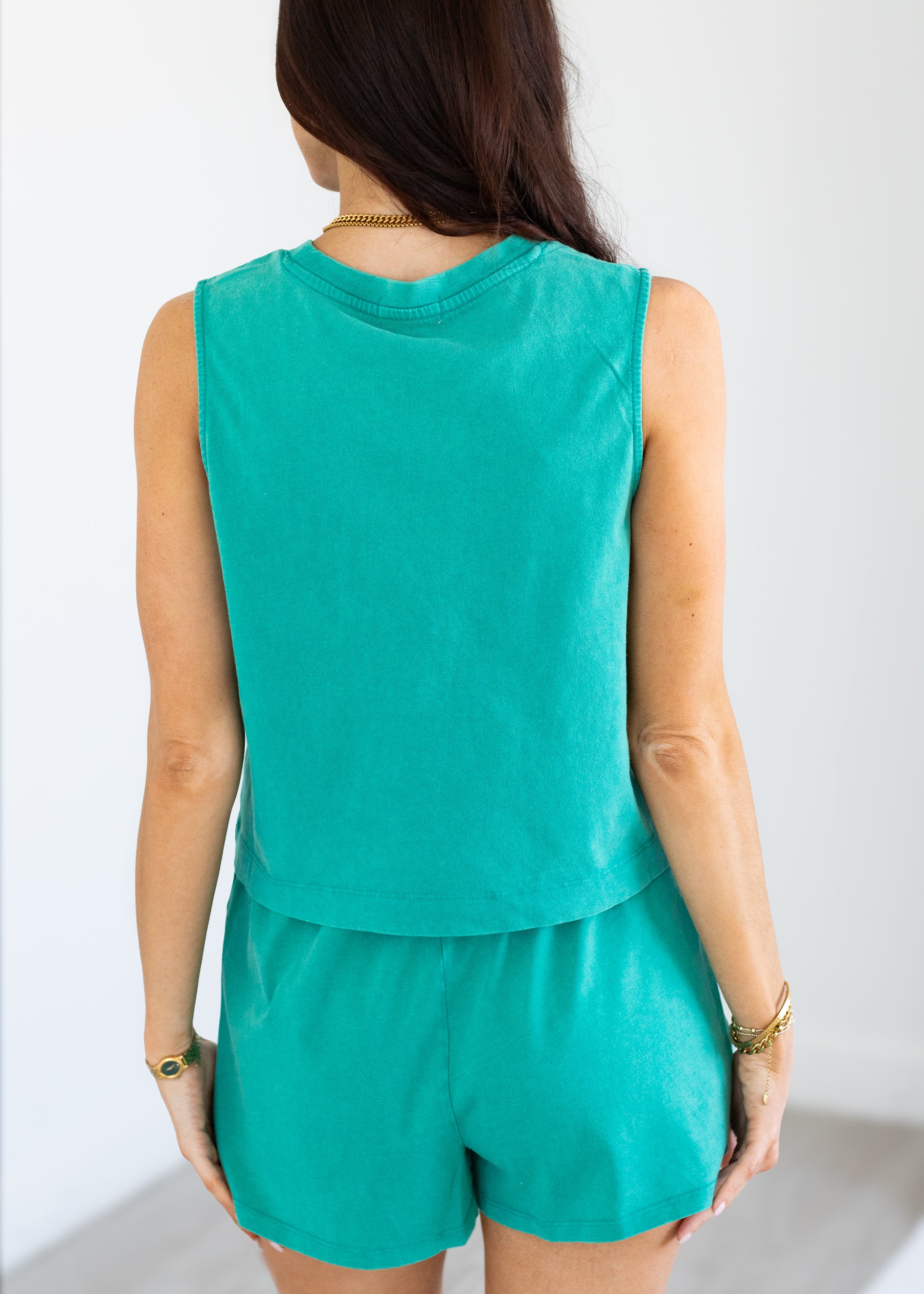 Person wearing a green sleeveless top and shorts set on a white background