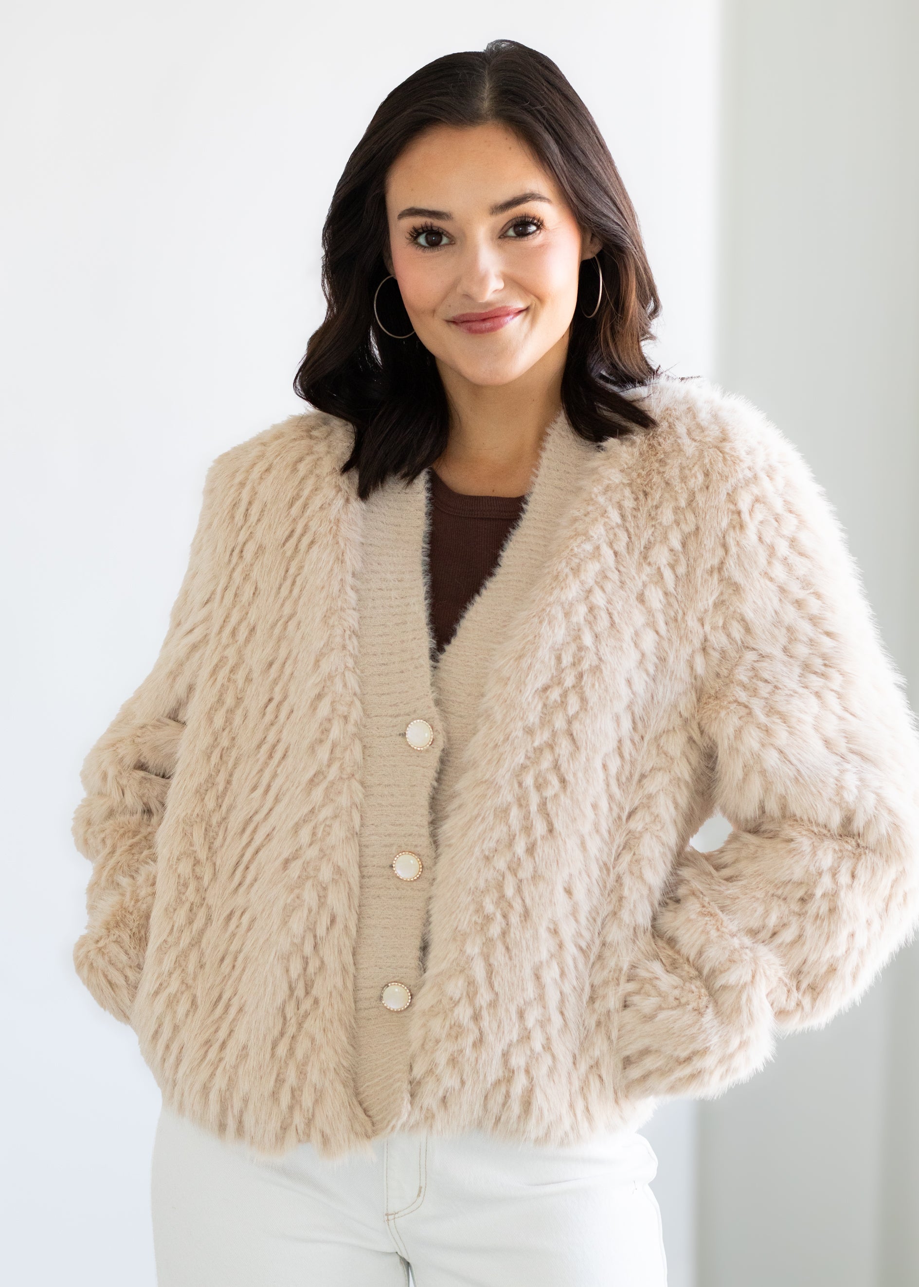 Woman wearing a beige knitted cardigan against a white background
