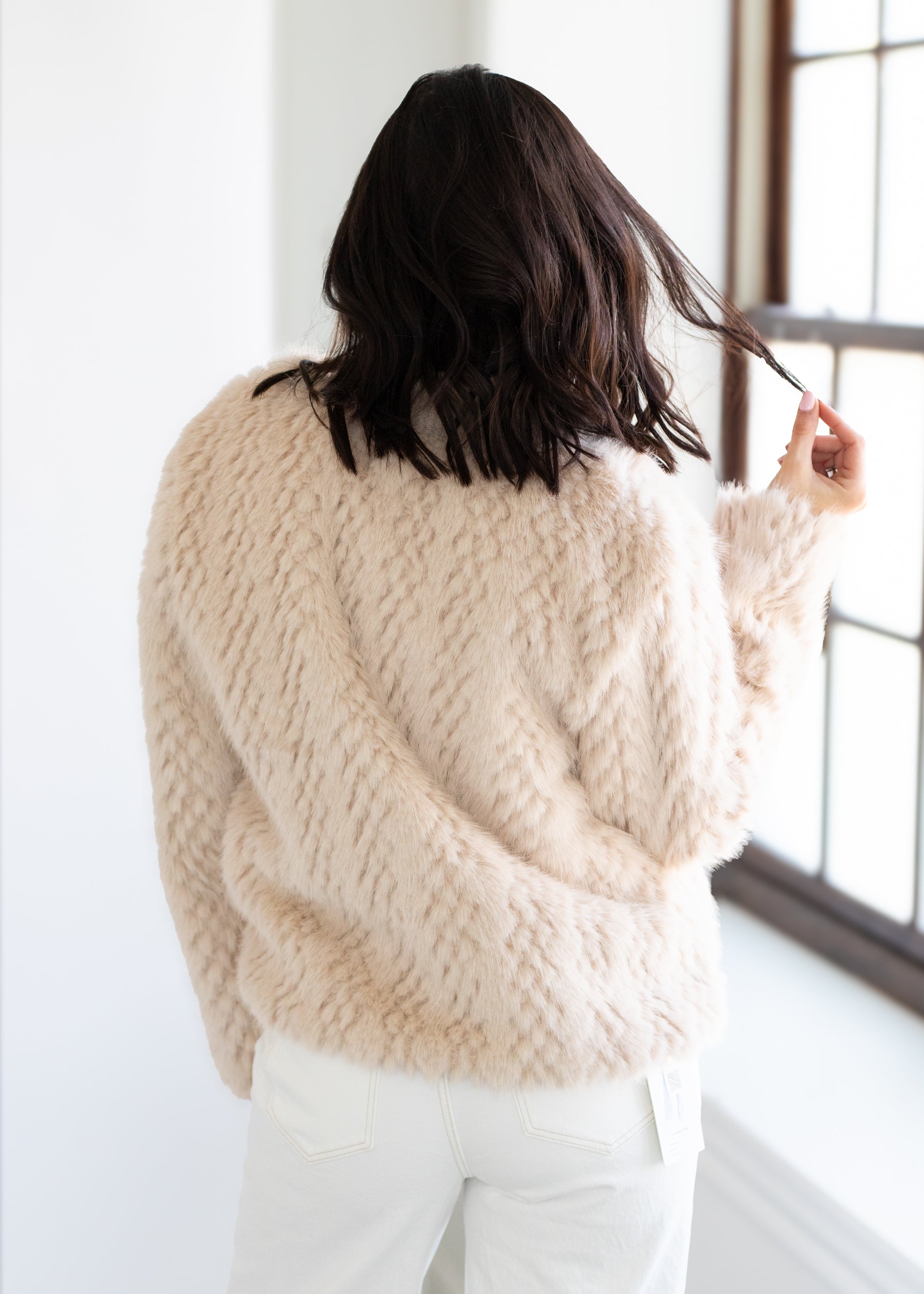 Person wearing a beige textured sweater in a minimal indoor setting