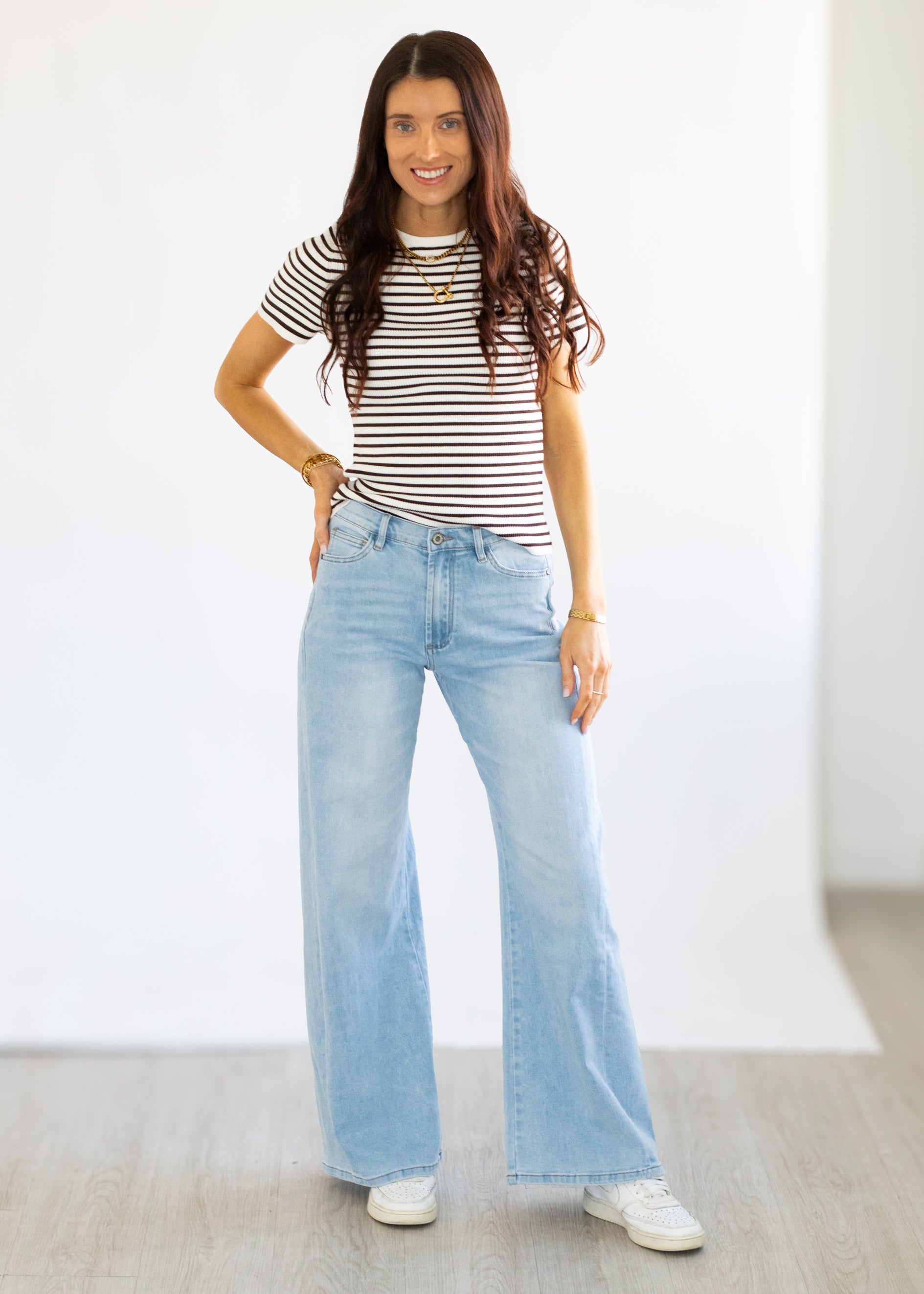 Woman wearing a striped shirt and light blue jeans against a white background