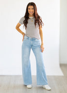 Woman wearing a striped shirt and light blue jeans against a white background
