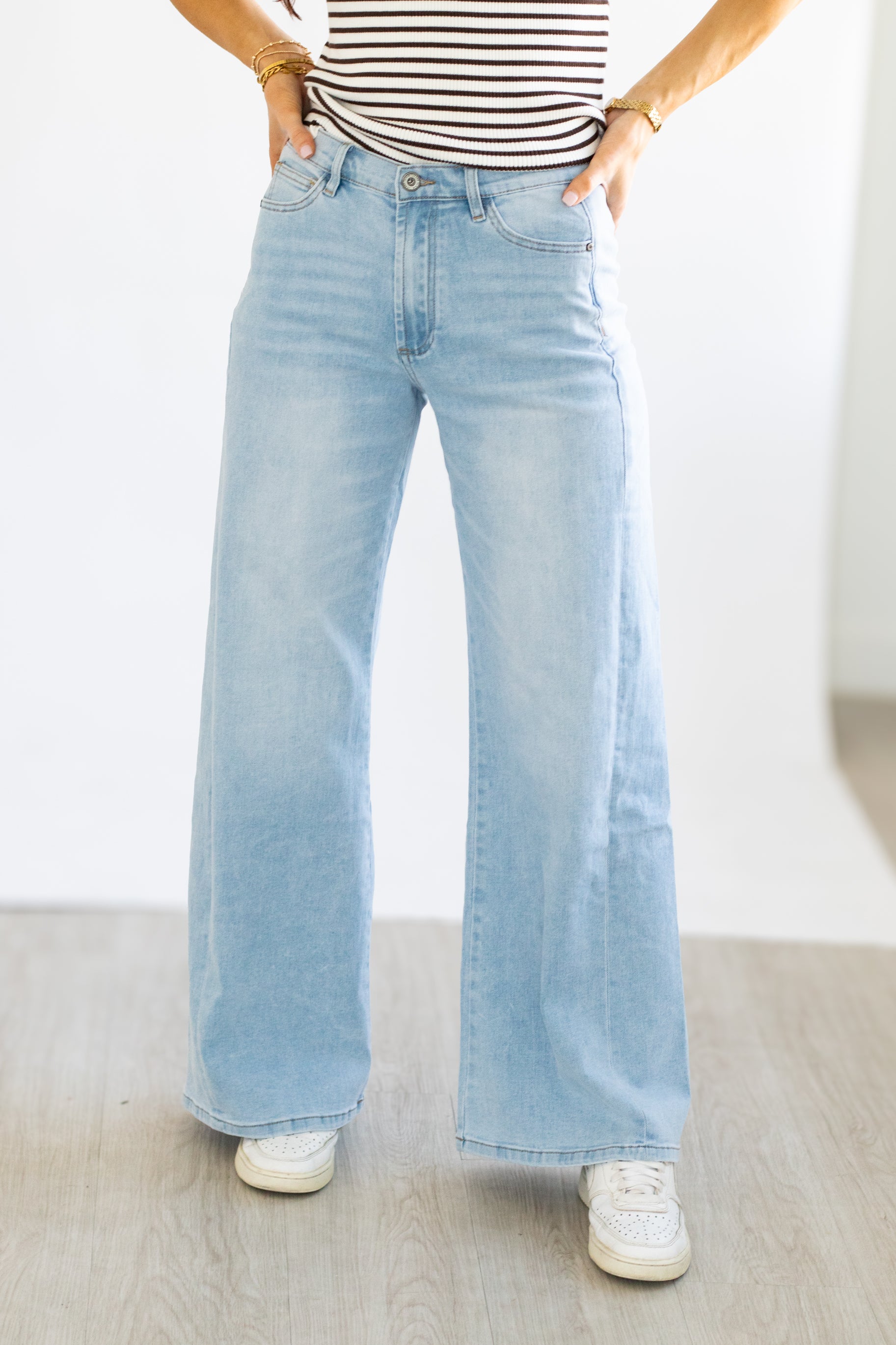 Person wearing light blue wide-leg jeans and a striped shirt on a plain background