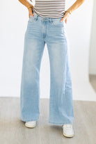 Person wearing light blue wide-leg jeans and a striped shirt on a plain background