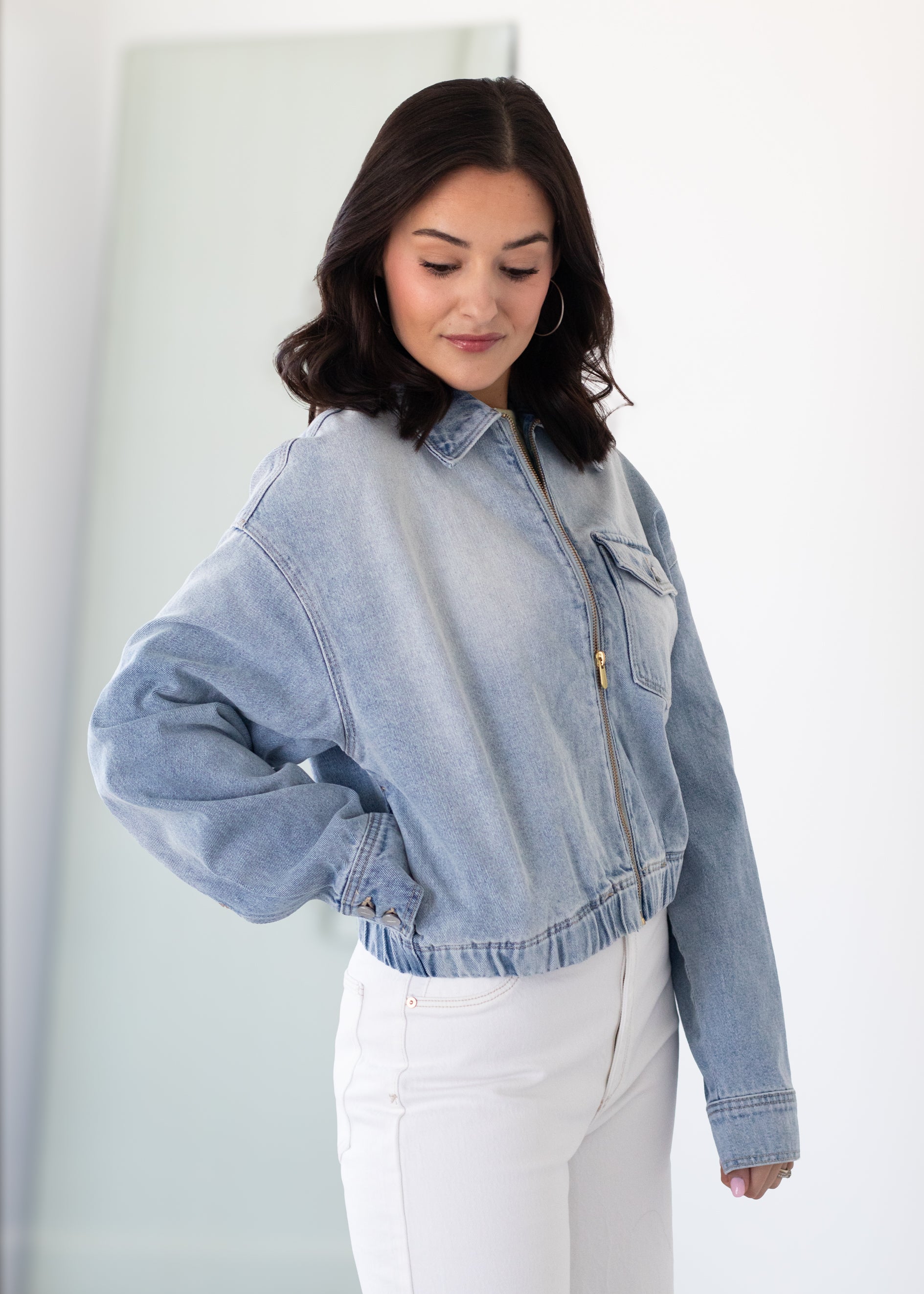 Woman wearing a light blue denim jacket against a white background
