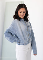 Woman wearing a light blue denim jacket against a white background