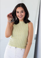 Woman wearing a light green sleeveless top with a white background