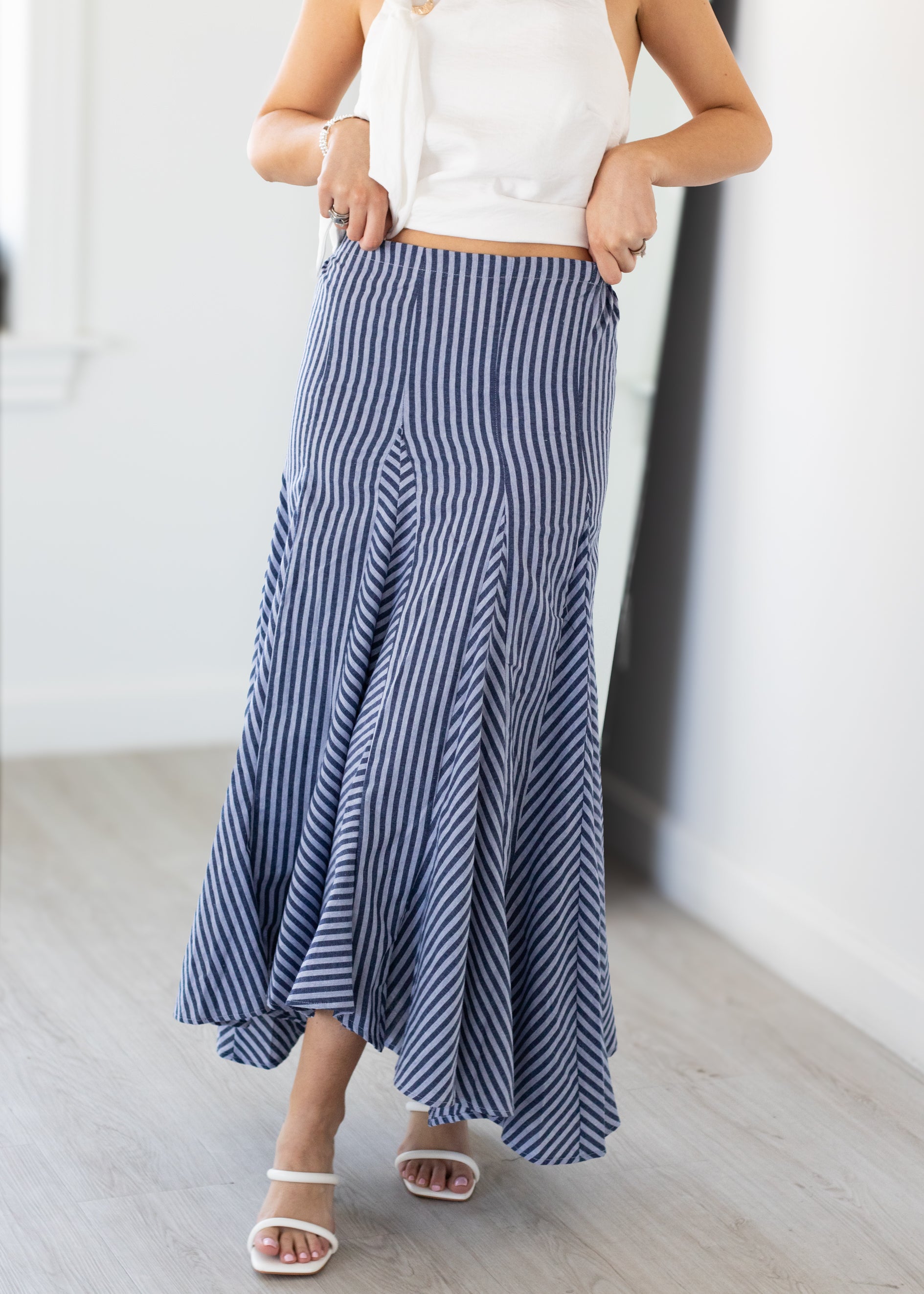 Person wearing a blue and white striped skirt with a white top indoors.