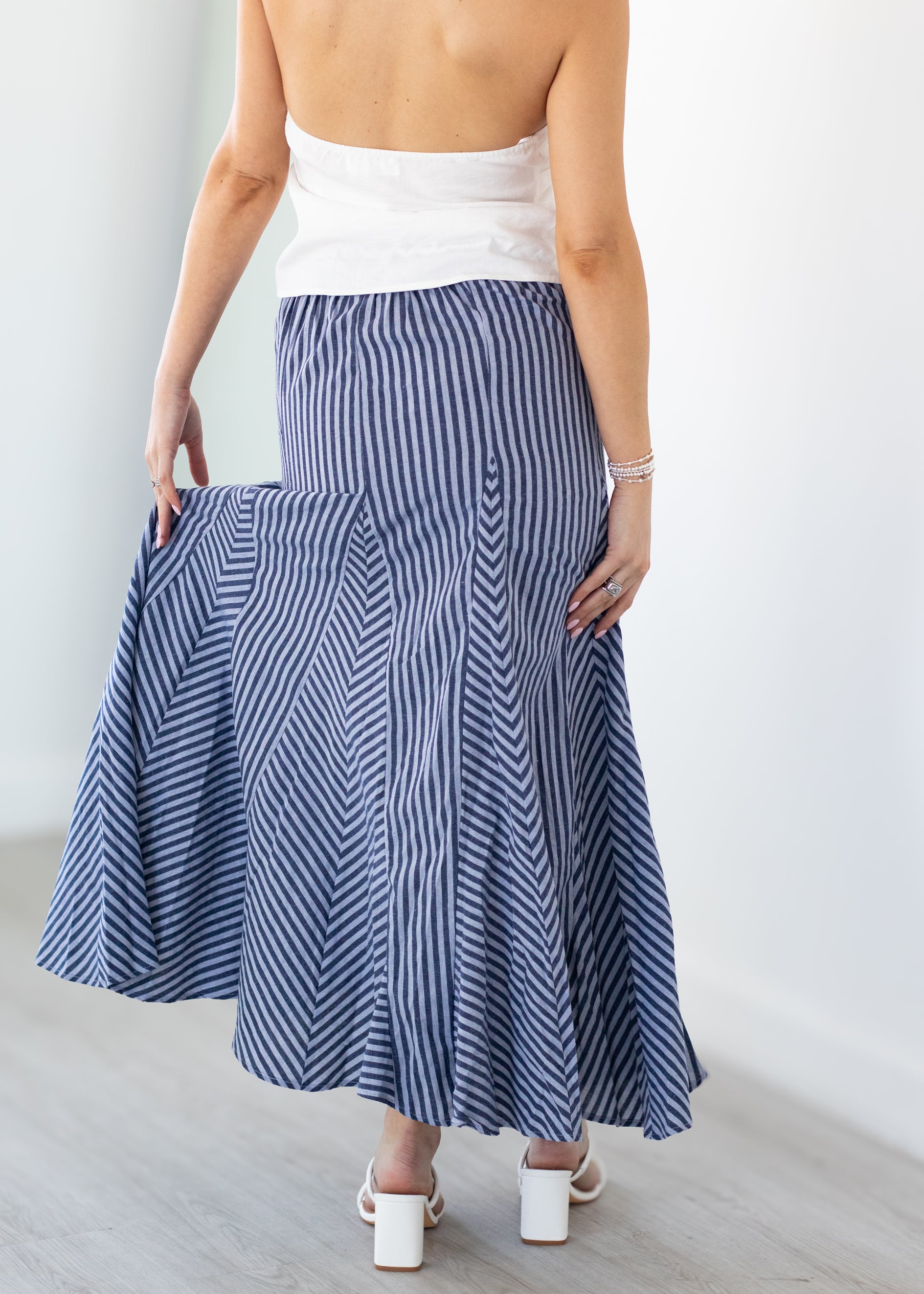 Woman wearing a blue and white striped skirt with a plain background