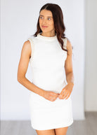 Woman wearing a white dress against a plain background