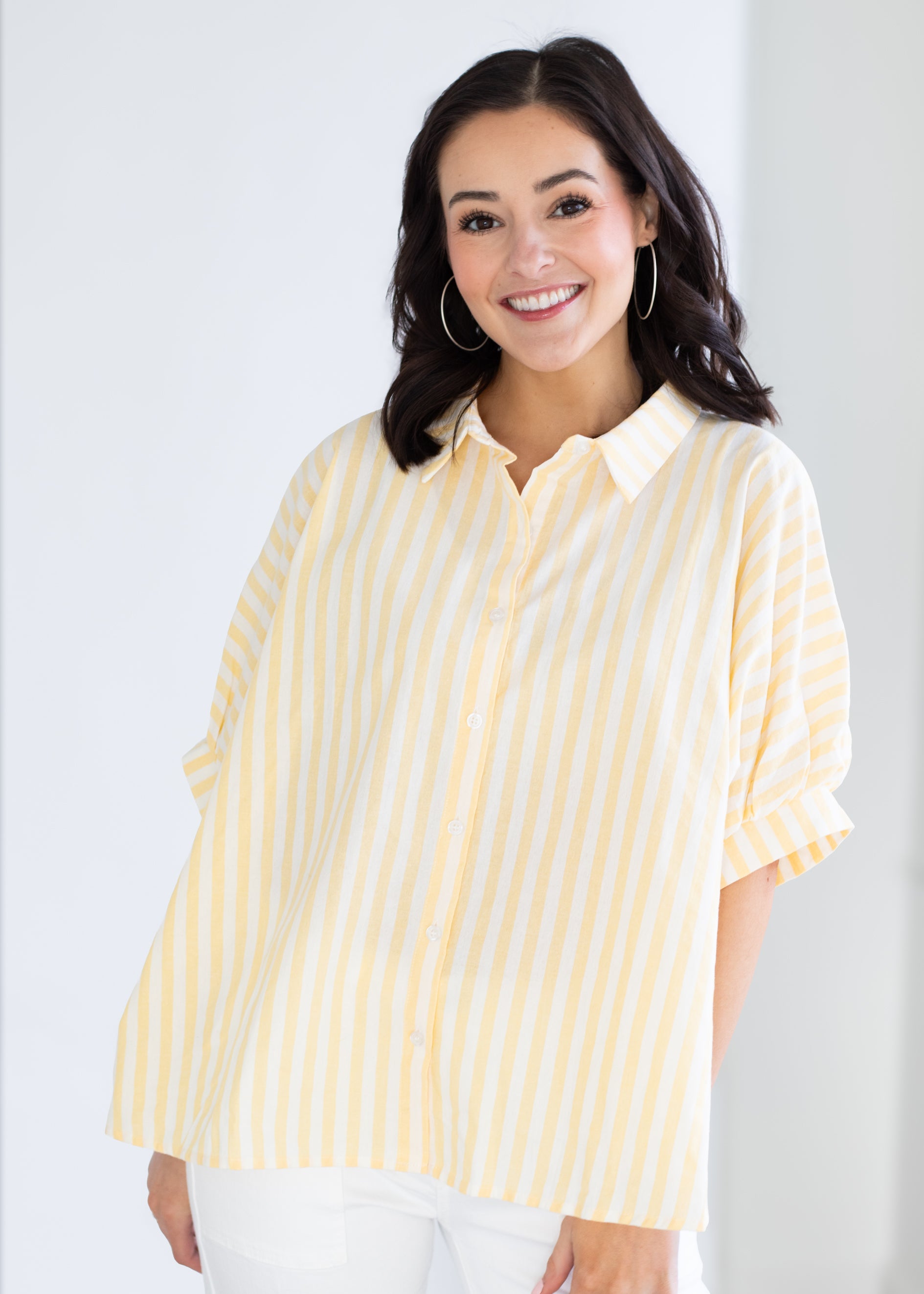 Woman wearing a yellow and white striped shirt against a white background