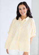 Woman wearing a yellow and white striped shirt against a white background