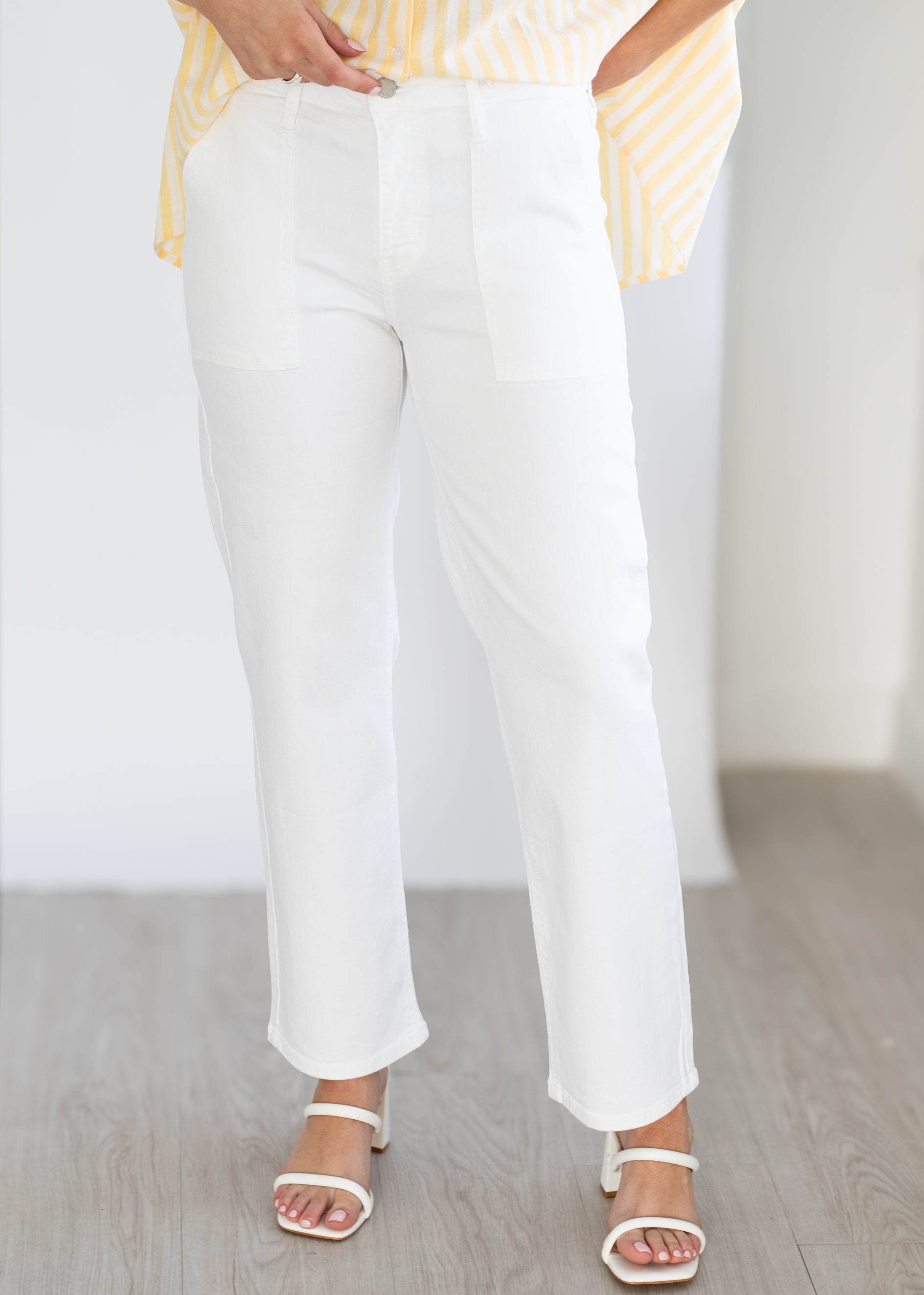 White pants worn by a person on a light wooden floor.